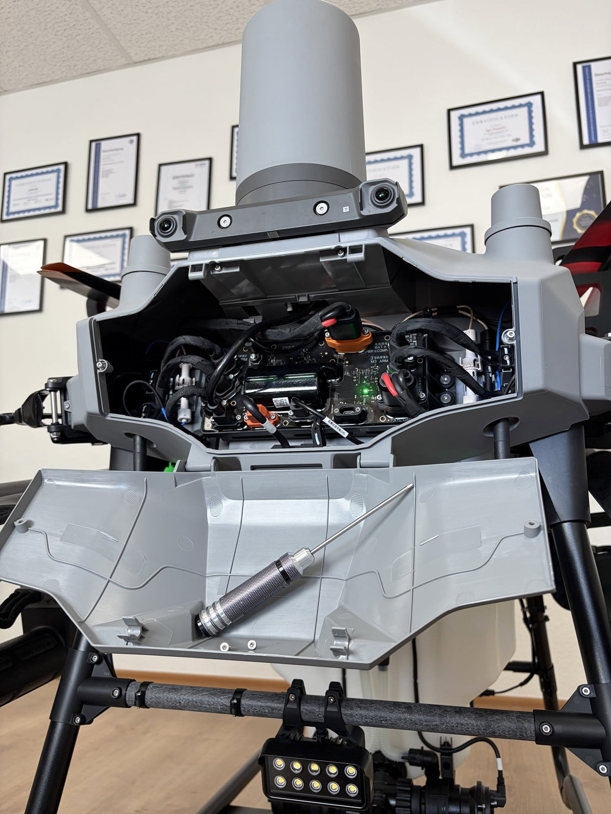 Geöffnete DJI Agras T70P Agrardrohne bei CopterTec mit freigelegter Elektronik und Werkzeug zur Reparatur.