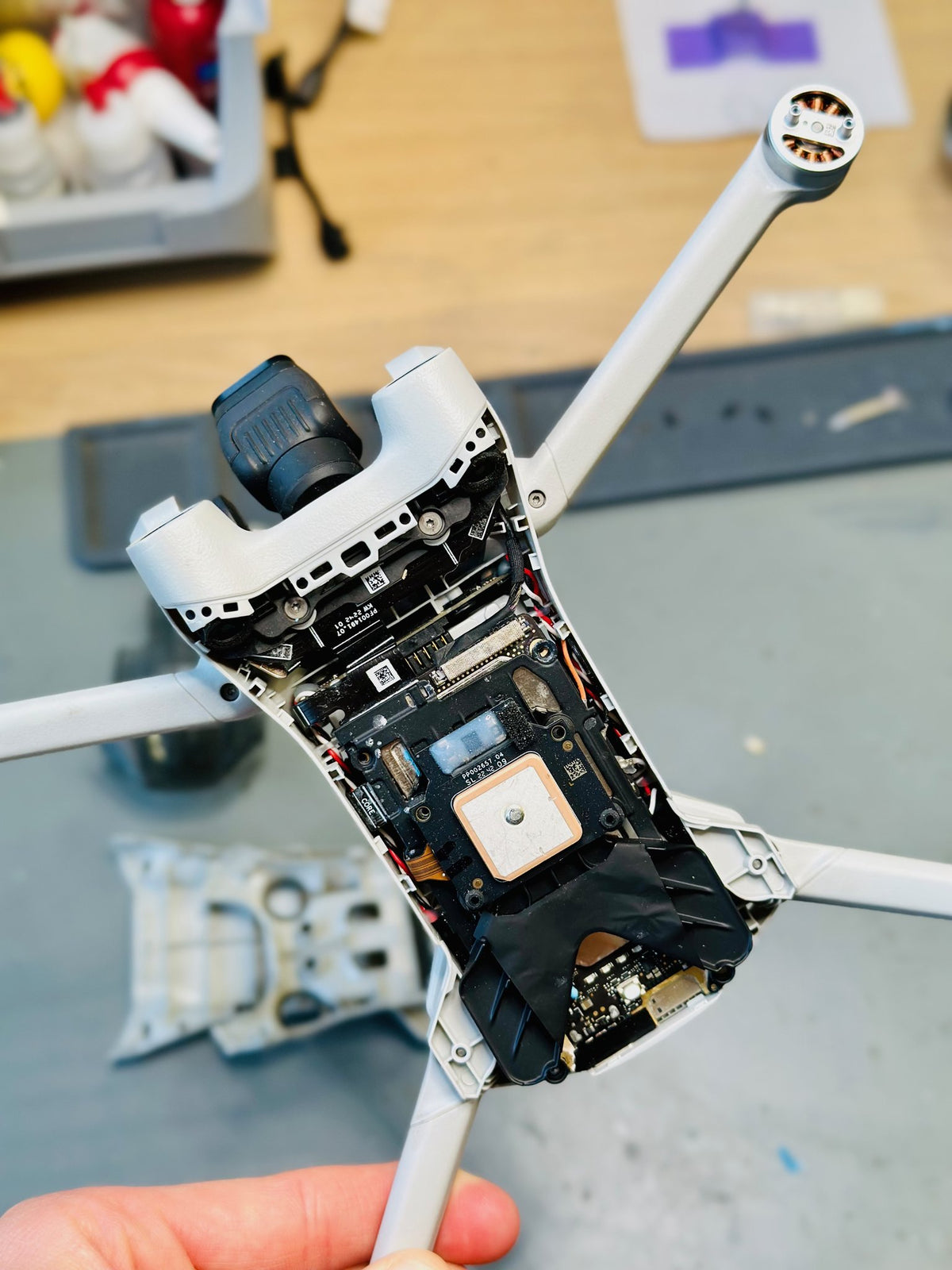 Geöffnete DJI Mini 3 Pro mit GPS-Modul bei der Reparatur in der Hand eines CopterTec-Technikers.