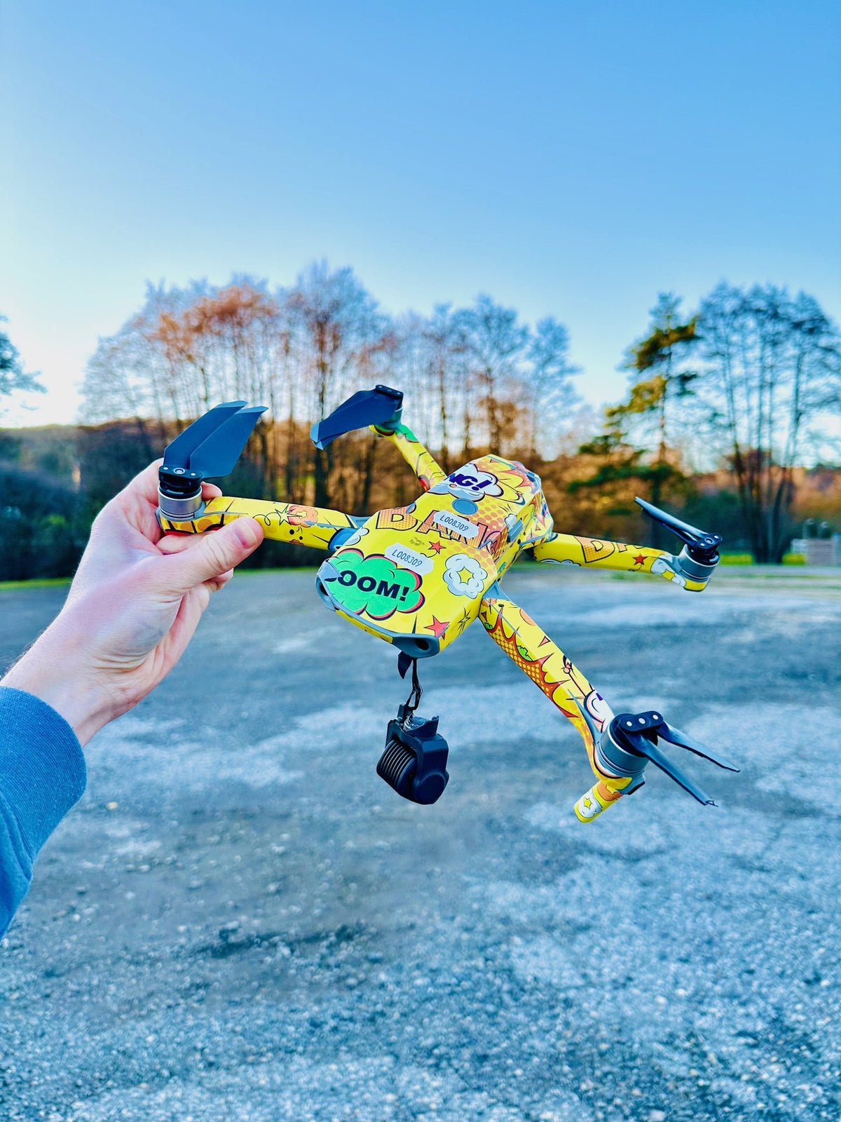 Gelb folierte DJI Mavic Air 2 mit abgerissenem Gimbal in der Hand eines CopterTec-Mitarbeiters vor der Reparatur.