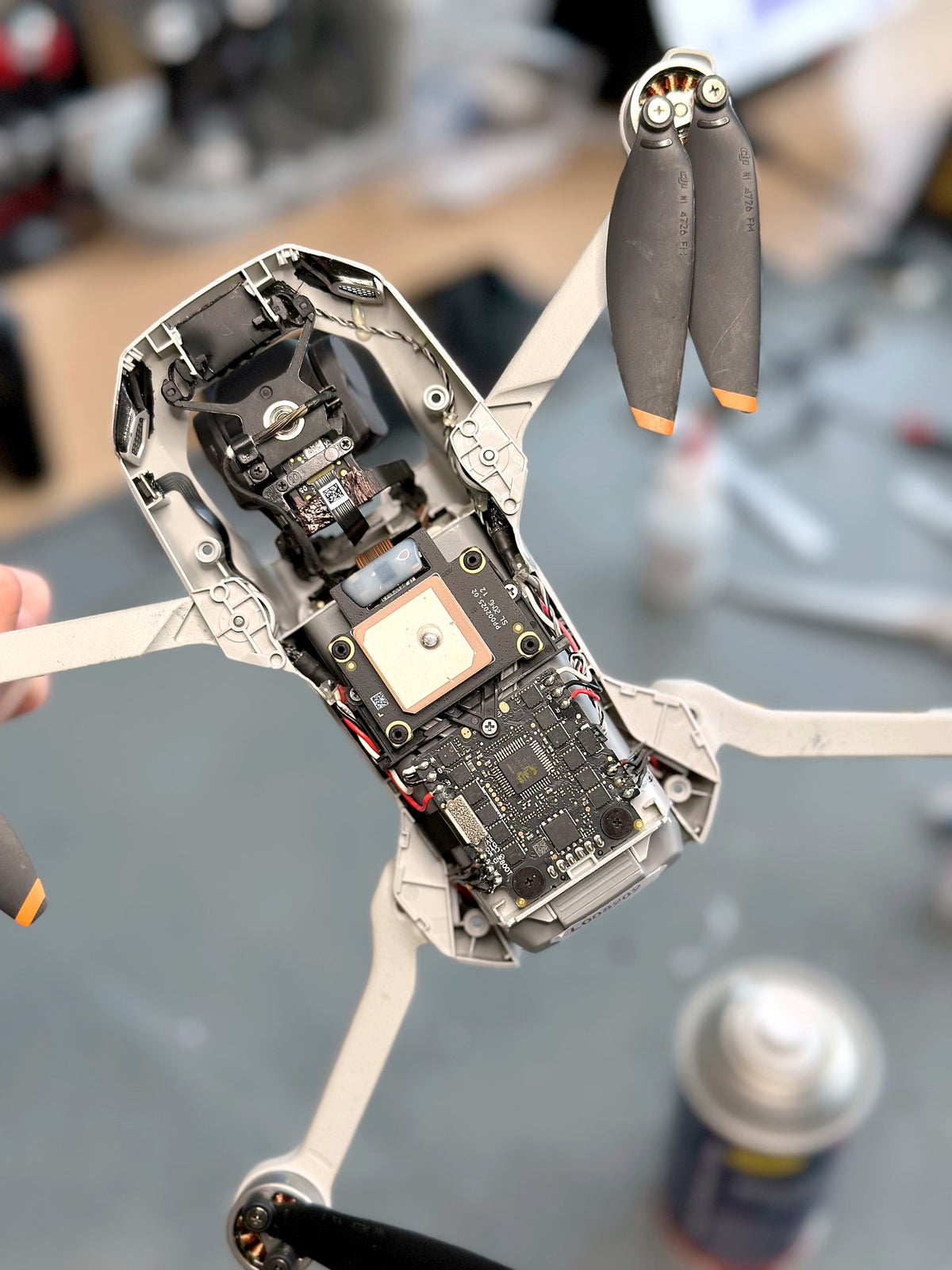 Geöffnete DJI Mini 2 in der Hand eines CopterTec-Technikers mit freigelegter Hauptplatine und GPS-Modul zur Fehlerdiagnose vor der Reparatur.