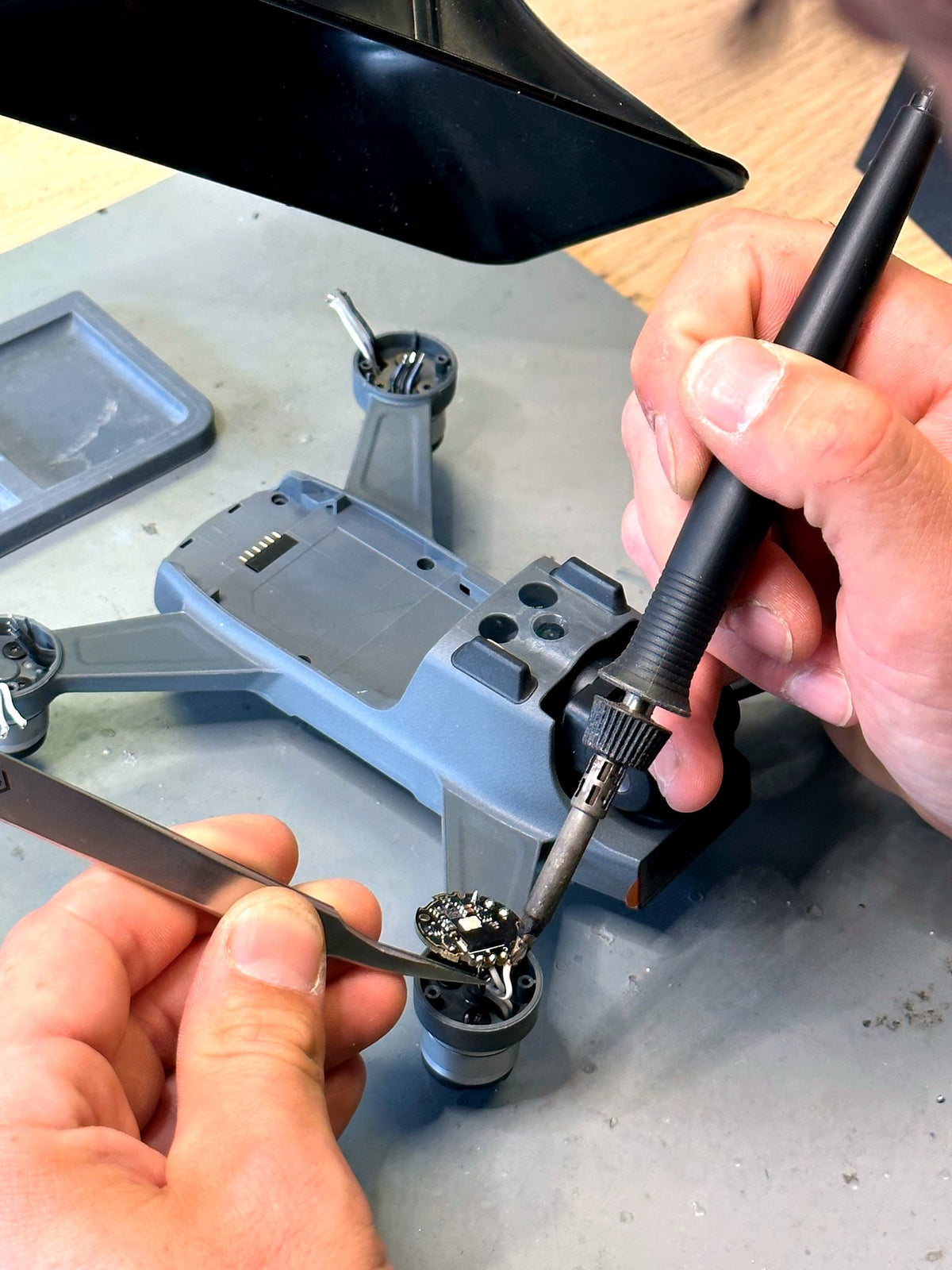 CopterTec-Techniker lötet bei der Reparatur einen neuen Motor an den Arm einer DJI Spark.